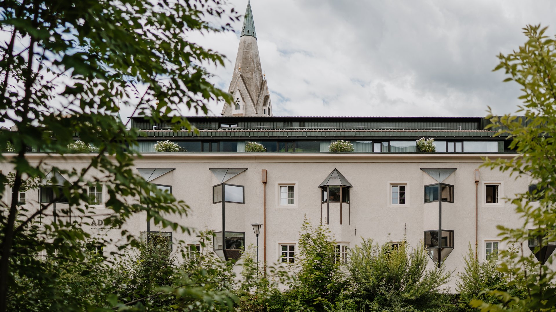 Vista di un edificio storico con una torre di chiesa dietro gli alberi
