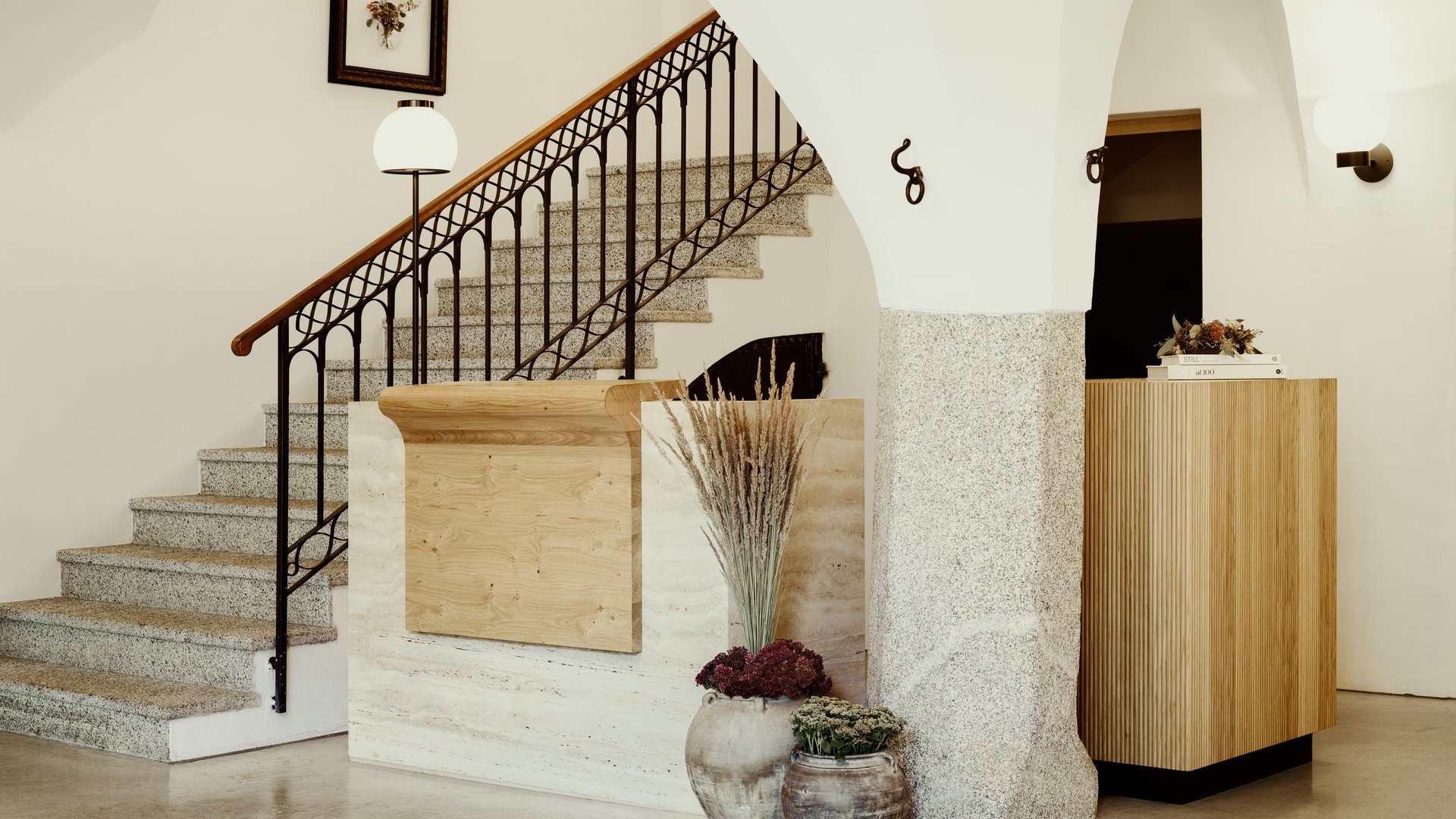 Reception moderna con scale, vasi di fiori e archi luminosi