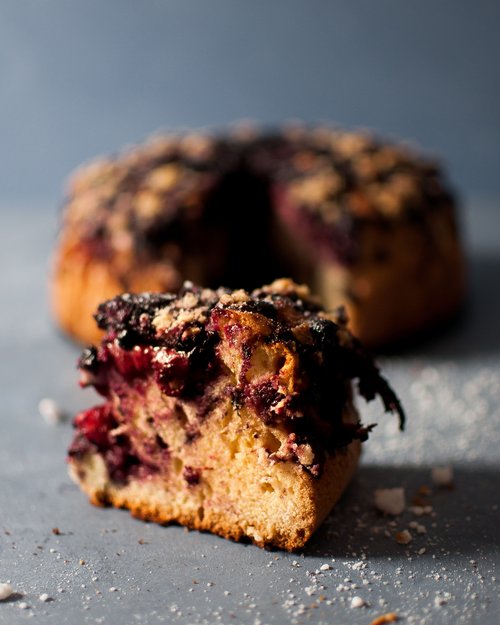 Fetta di torta ai mirtilli con briciole su superficie grigia